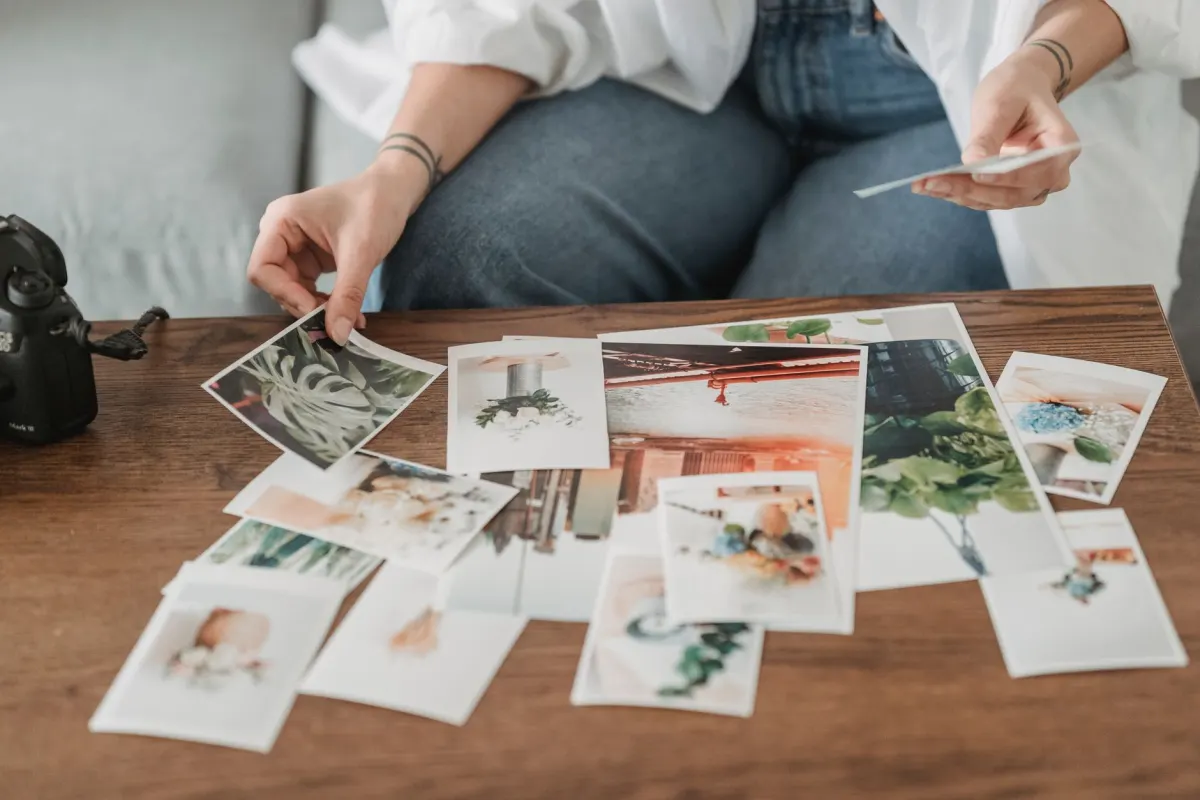 Hände sortieren gedruckte Fotos in Behalten- und Wegwerf-Stapel, was der Entscheidung zwischen Archivieren und Löschen eines Beitrags entspricht.