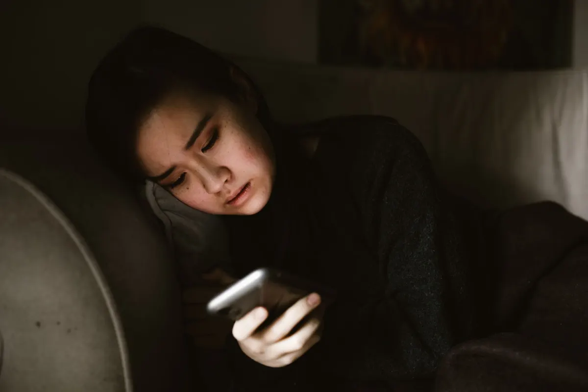 Uma mulher navega no smartphone no sofá à noite, refletindo os dados de horários ativos rastreados pelas métricas comportamentais.