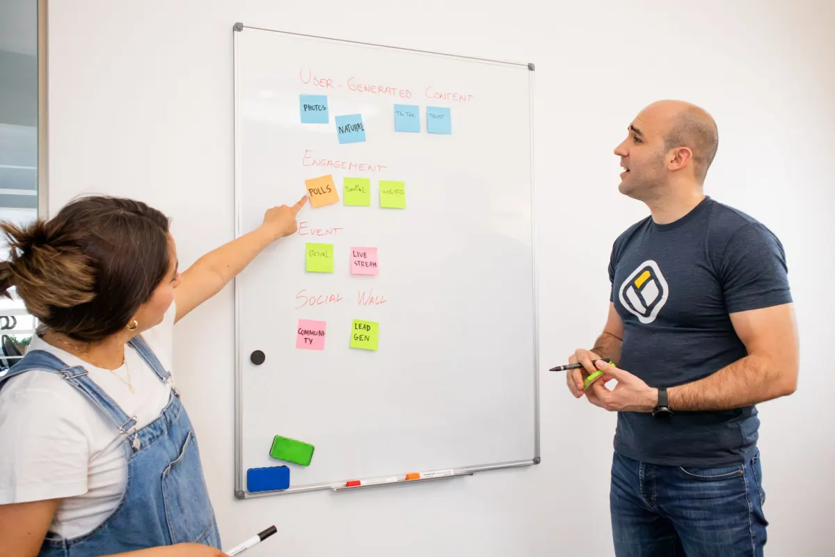 Uma pequena equipe revisa um calendário de conteúdo em um quadro branco, planejando publicações nos horários de maior engajamento.