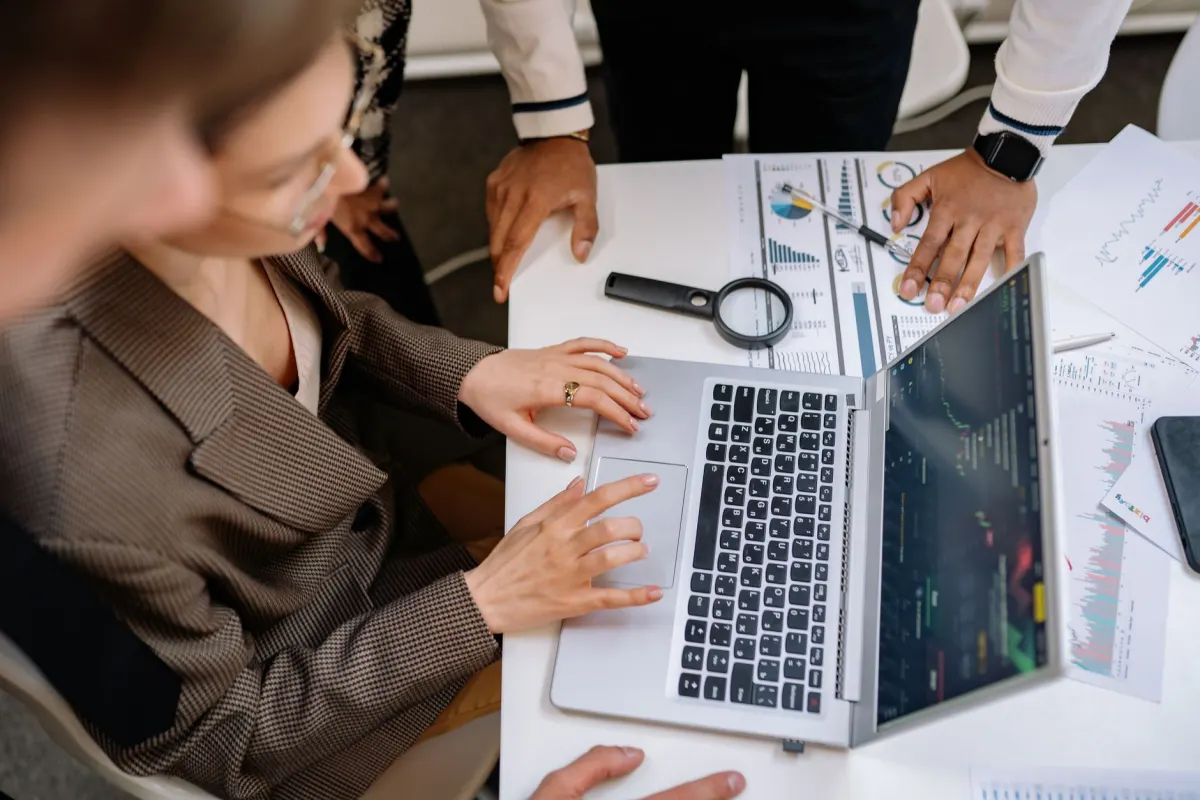 Deux collègues qui vérifient ensemble l'écran d'un ordinateur portable, le genre de contrôle croisé qui permet aux agences de repérer une erreur de publication avant que le client ne la voie.