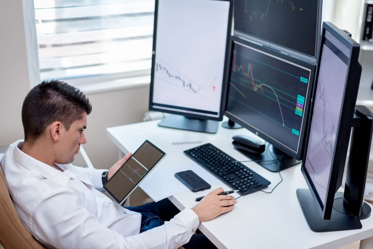 Eine Person verwaltet mehrere Bildschirme an einem Schreibtisch, was die Arbeit beim Management mehrerer Social-Media-Konten aus einer Zentrale widerspiegelt.