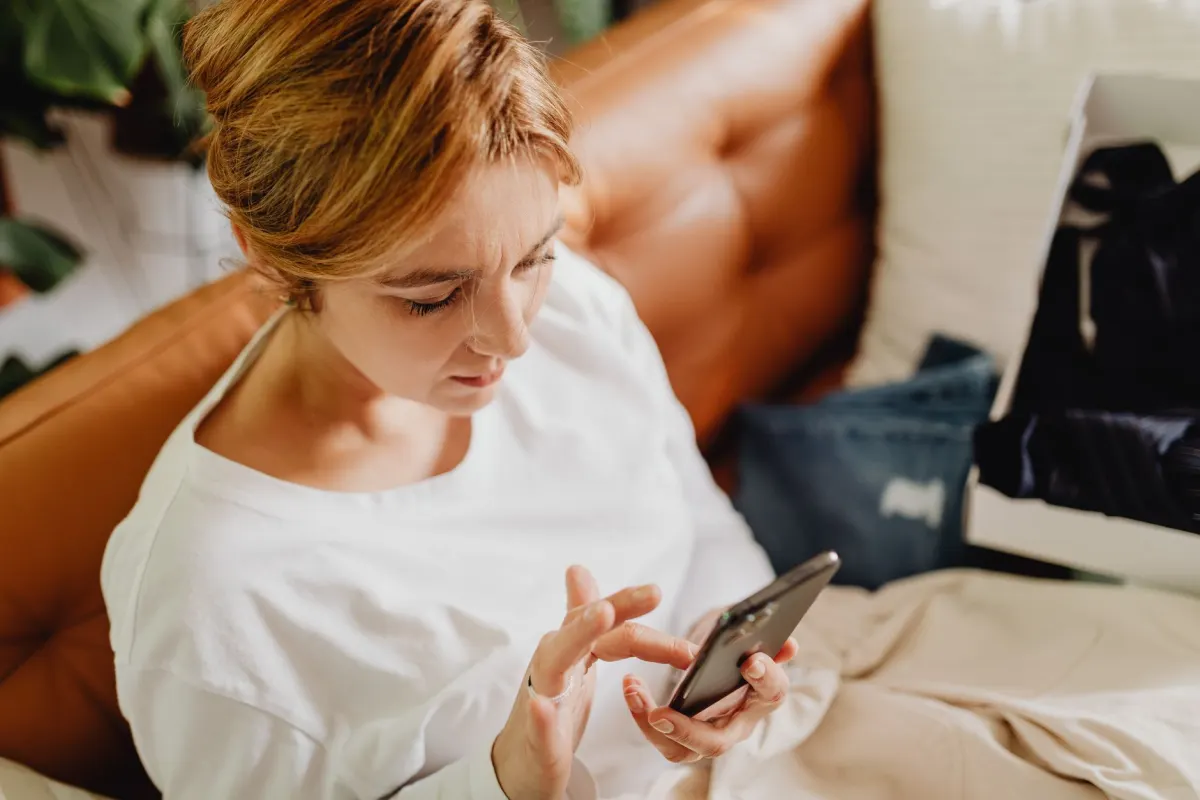Une femme consulte son téléphone sur le canapé le soir, le genre de moment que les données d'activité des abonnés permettent de repérer.