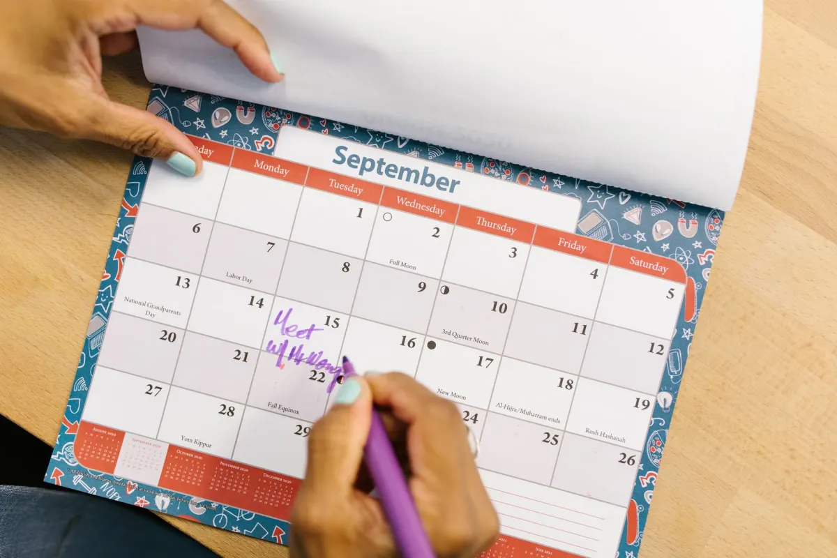 Eine Person markiert Termine auf einem Wandkalender, passend zur Planungsroutine hinter einem verlässlichen Veröffentlichungsplan.