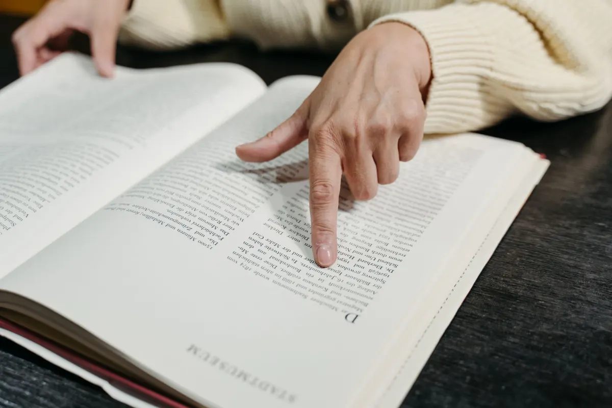 A hand underlining a quoted passage in a printed book, illustrating quoting another person's post.