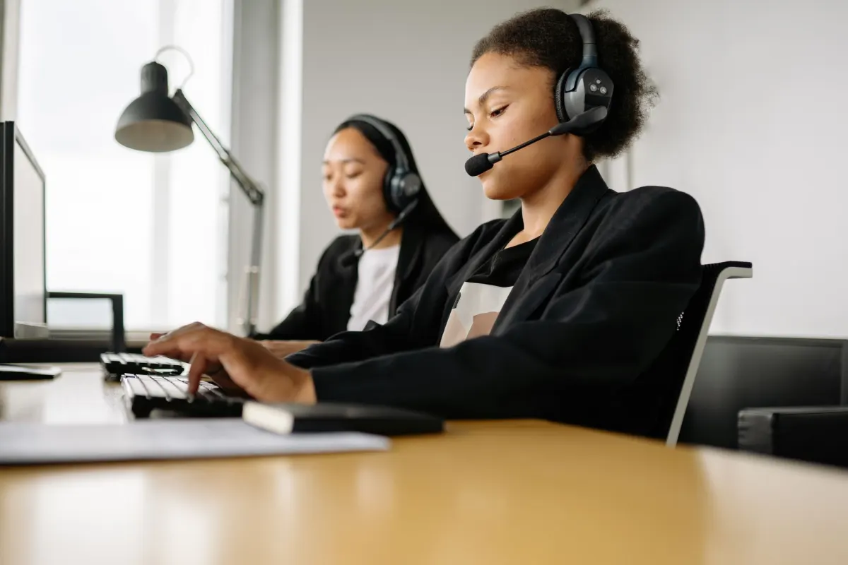 Um agente de suporte digitando em uma mesa com headset, representando a velocidade e a consistência que respostas prontas trazem para perguntas repetitivas.