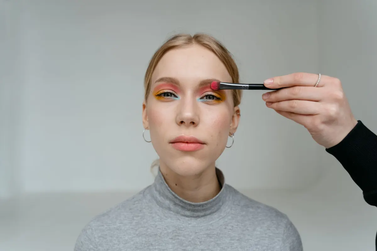 Eine Person mit verbundenen Augen trägt Make-up nach Gefühl auf, genau die Art von wackligem Versuch, die die Blindes-Make-up-Challenge ausmacht.