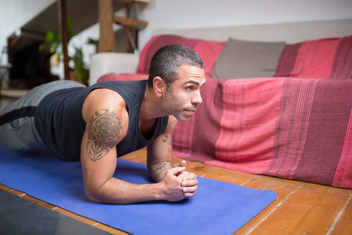 Jemand hält eine Plank-Position auf einer Matte, die Übung, um die es bei der Plank-Challenge geht.