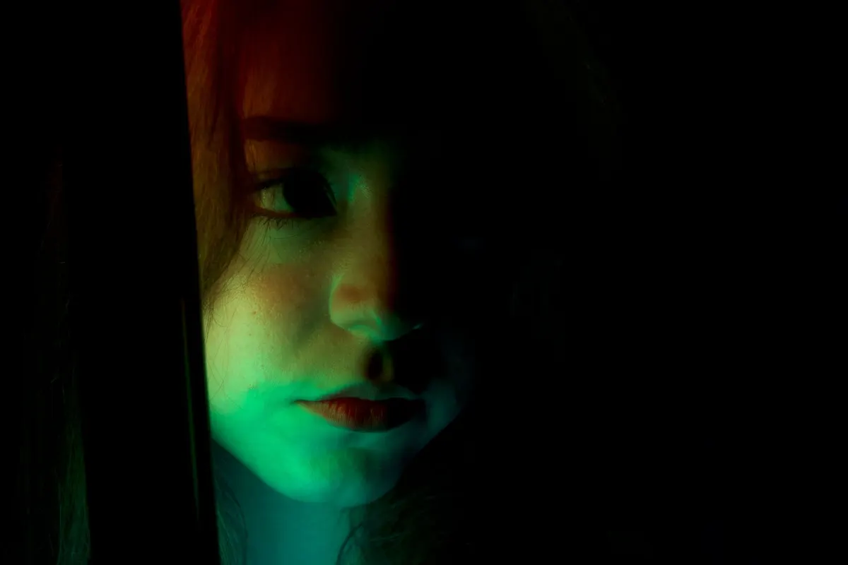 Uma pessoa é iluminada por uma luz de gel colorida, remetendo ao efeito de foto tingida descrito neste método.