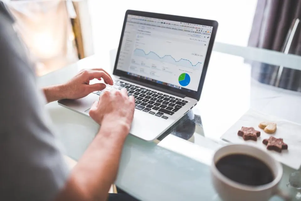 Ein Marketer scrollt auf einem Laptop durch ein Traffic-Analytics-Dashboard, genau die Art von Daten, die in ein Wettbewerber-Profil einfließen.