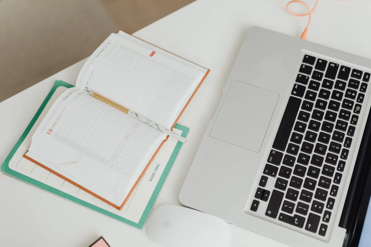 Un agenda et un ordinateur portable sur un bureau illustrent la dernière étape : charger un mois de contenu dans un outil de planification.