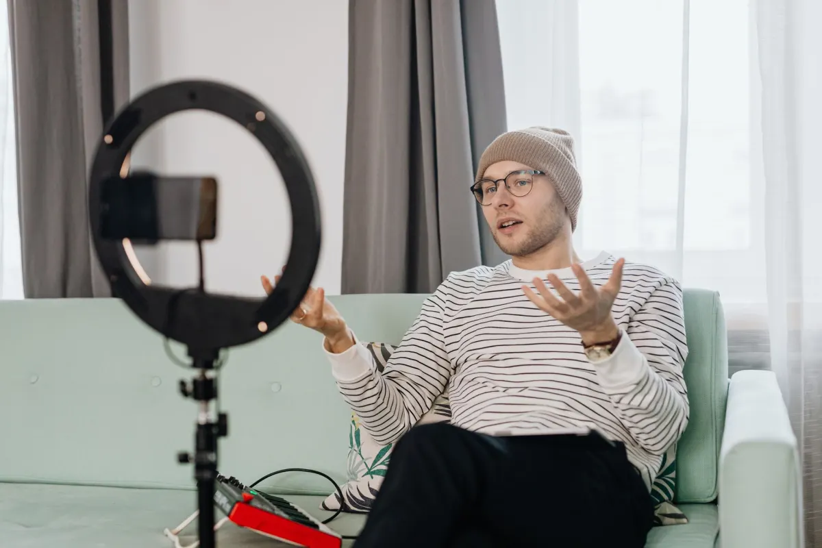 Ein Host sitzt vor einem Ringlicht und einer Kamera mitten in einem Livestream und spricht in Echtzeit direkt mit dem Publikum.