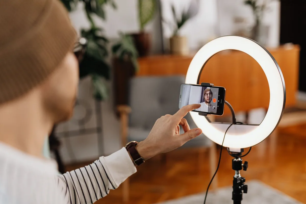 Un créateur filmant une vidéo avec un téléphone et une ring light, la moitié production du marketing de contenu