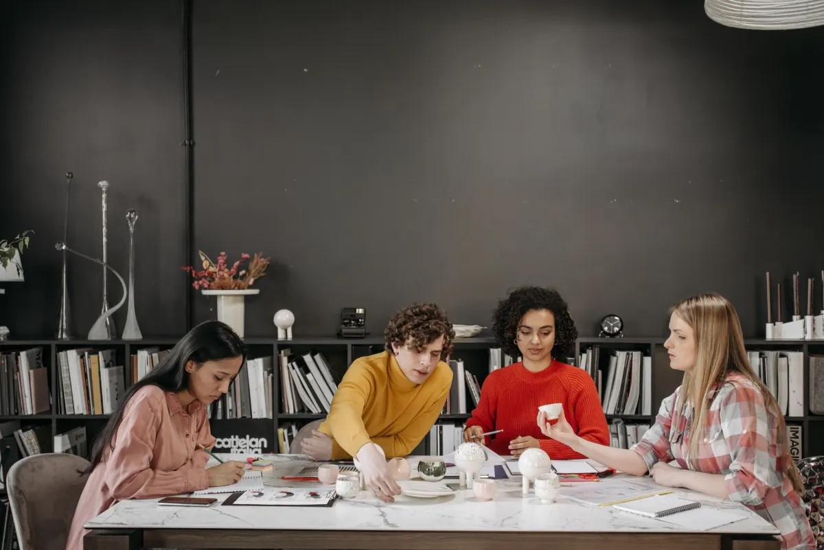 Eine kleine Gruppe sitzt im Gespräch um einen Tisch und zeigt die Art von Teamarbeit, die beim Aufbau eines Moderationsteams gefragt ist.