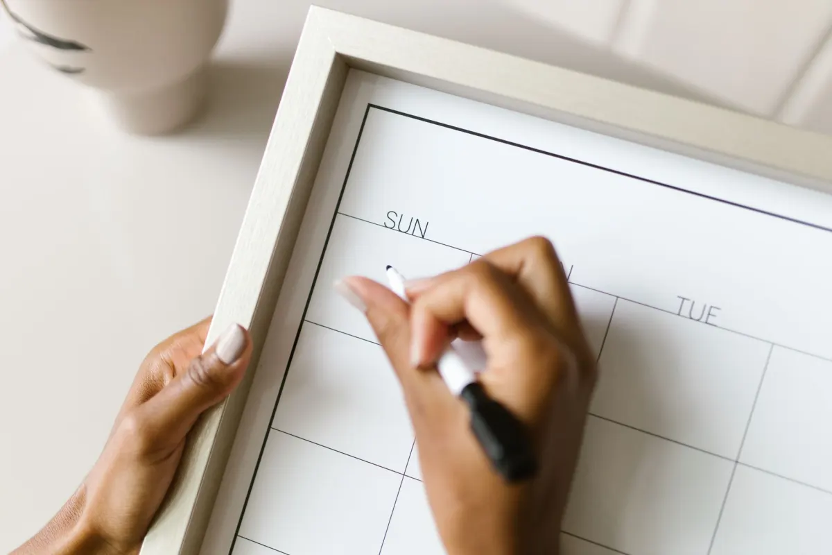 Membros da equipe organizam notas adesivas em um calendário de parede, mostrando como os pilares de conteúdo são agendados em um calendário de conteúdo.