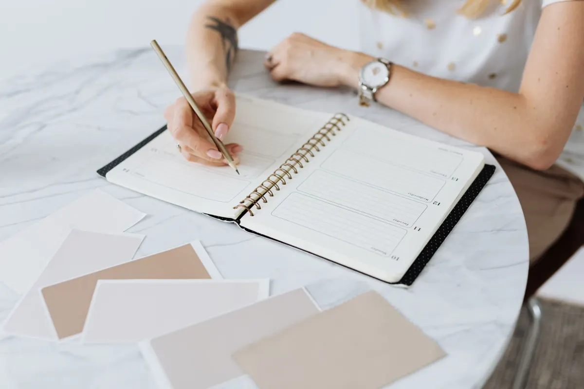 Une personne écrit dans un agenda à son bureau, illustrant l'étape de planification dans un calendrier de contenu.