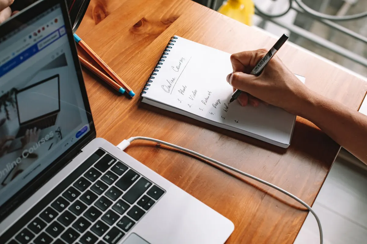 Eine Person macht sich handschriftliche Notizen, während sie einen Kurs auf einem Laptop verfolgt, so wie eine Webinar-Aufzeichnung zu einem strukturierten Lernpfad wird.