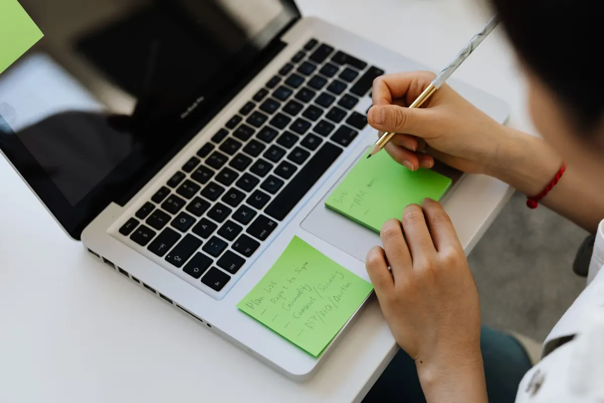 Une marketeuse consulte un calendrier de contenu sur un ordinateur portable en comparant des outils de planification.