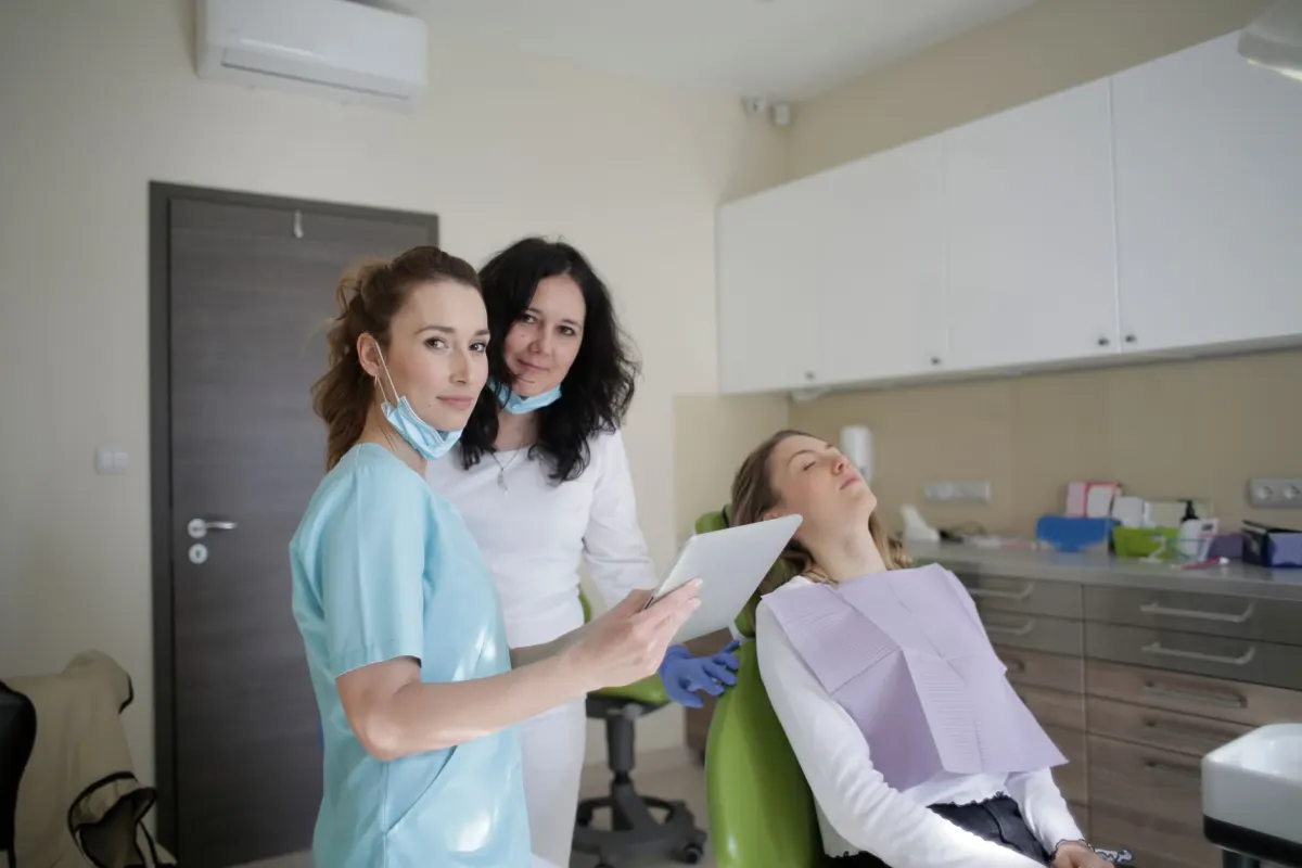Une équipe dentaire souriante posant ensemble dans son cabinet, le genre de photo des coulisses qui construit la confiance avant qu'un patient ne prenne rendez-vous.