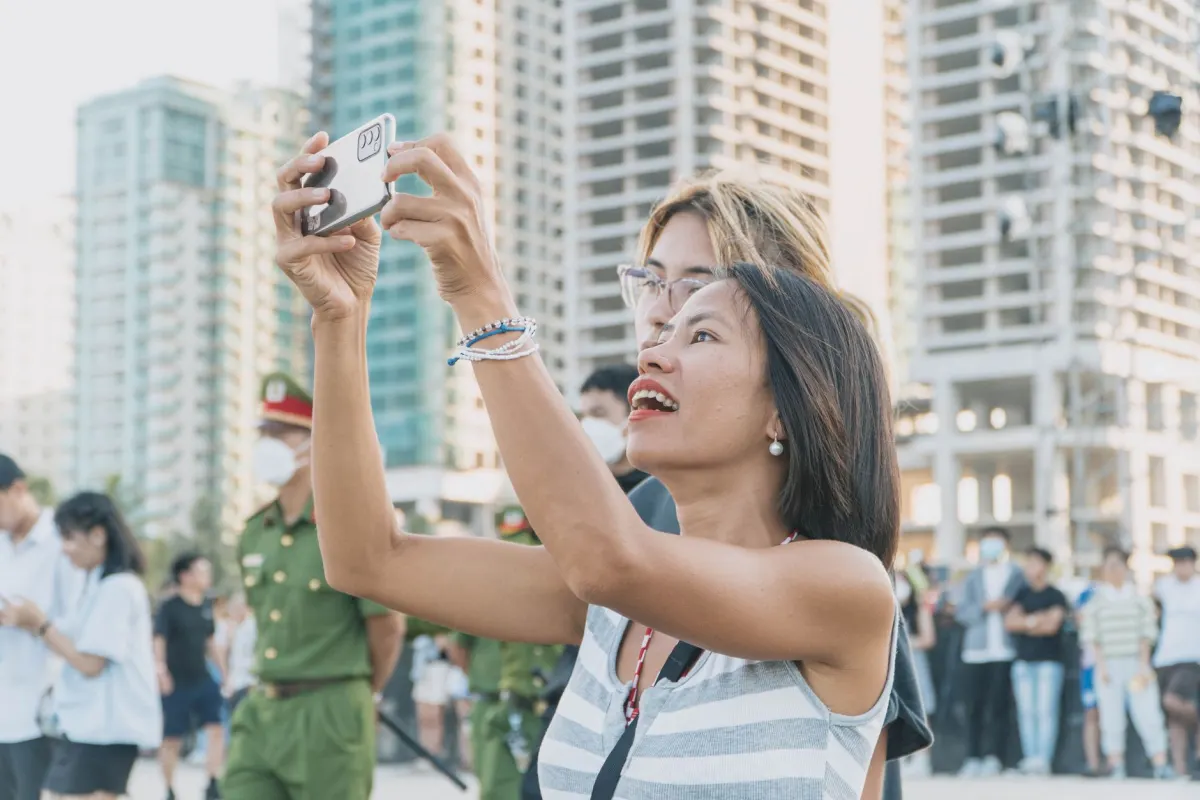 Eine Person hält ein Smartphone hoch, um ein entferntes Motiv zu fotografieren, genau dort trennen sich optischer und Digital-Zoom.