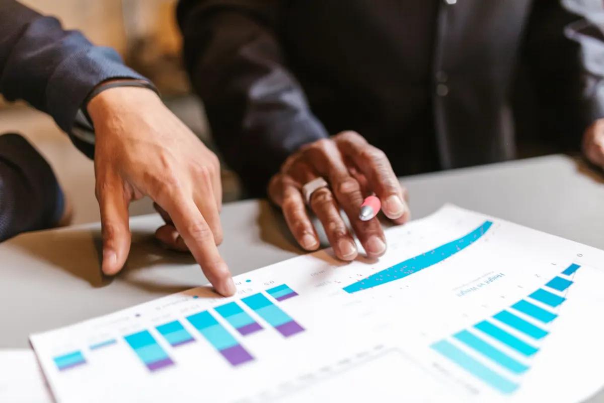 Eine Marketing-Analystin zeigt auf ein gedrucktes Balkendiagramm und veranschaulicht, wie diskrete Daten dargestellt werden.