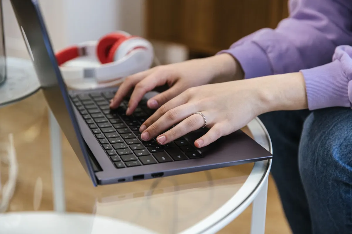 Eine Person tippt auf einem Laptop, was für eigene Kanäle wie eine Website oder einen Blog steht, die ein Unternehmen direkt kontrolliert.