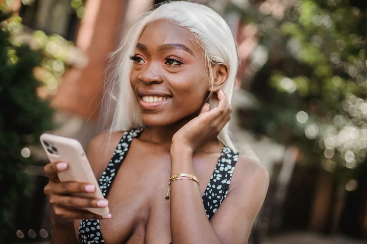 Uma mulher sorri enquanto digita uma mensagem no celular, o tipo de troca privada para a qual um DM existe.