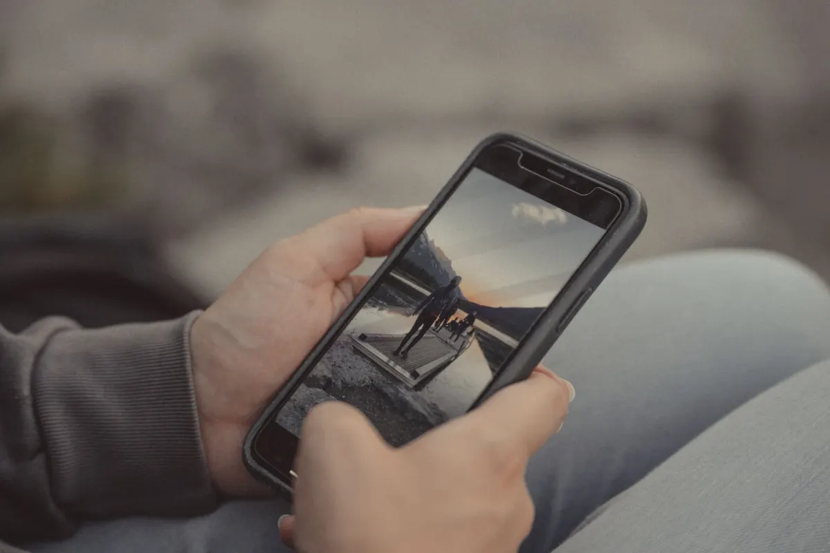 Une personne tient un smartphone à l'extérieur, en lien avec les étapes de téléchargement mobile de cette section.