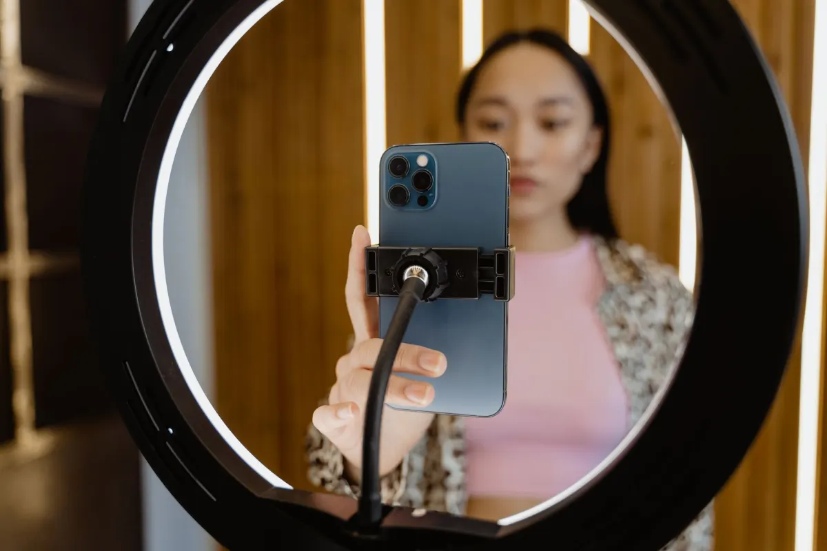 Une personne filme une vidéo verticale avec un anneau lumineux, illustrant le conseil d'utiliser des visuels percutants.