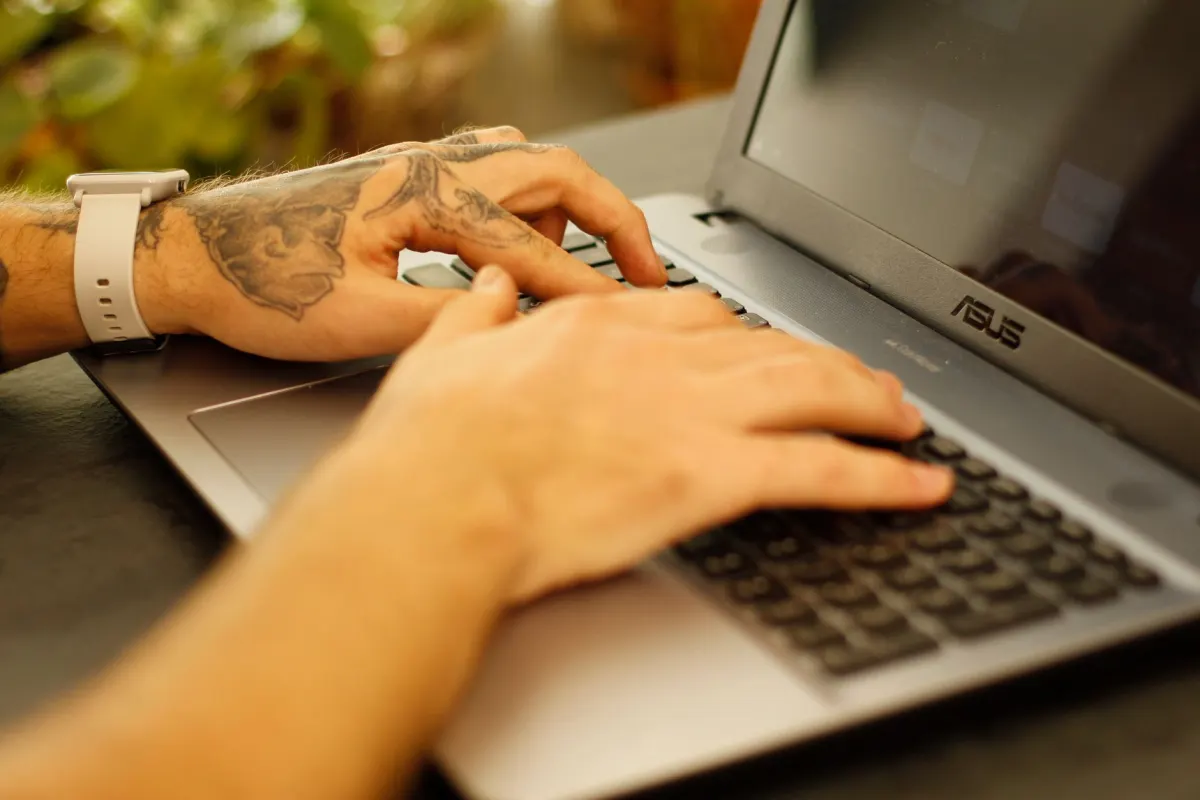 Una persona escribe en una laptop, redactando el tipo de titular que se compara en los ejemplos siguientes.