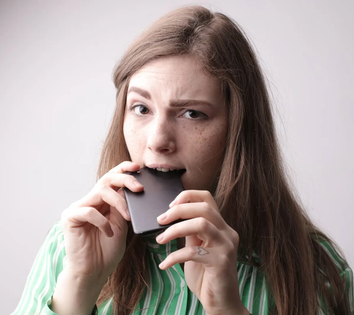 Eine Frau schaut besorgt auf ihr Smartphone, was die Warnsignale für zu häufiges Posten auf einem persönlichen Profil veranschaulicht.