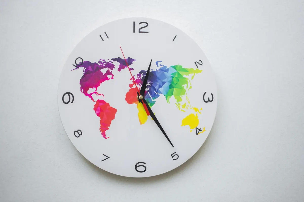 Eine Wanduhr neben einer Weltkarte steht für die richtige Zeitzoneneinstellung für geplante Beiträge.