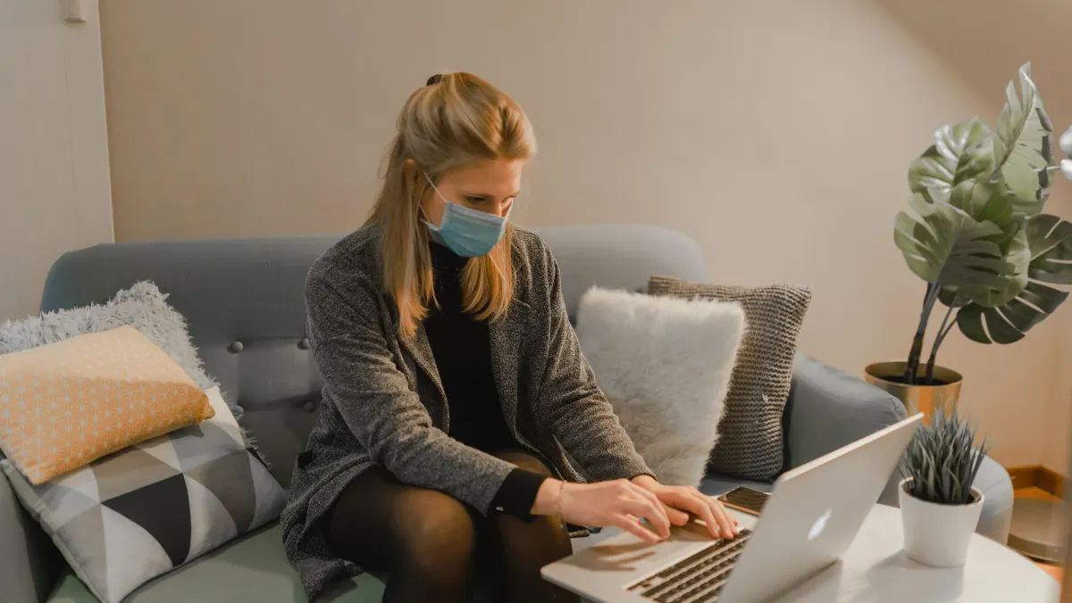 Une femme tape une courte mise à jour sur son ordinateur portable, assise sur le canapé, le genre de publication rapide décrite dans cette section.