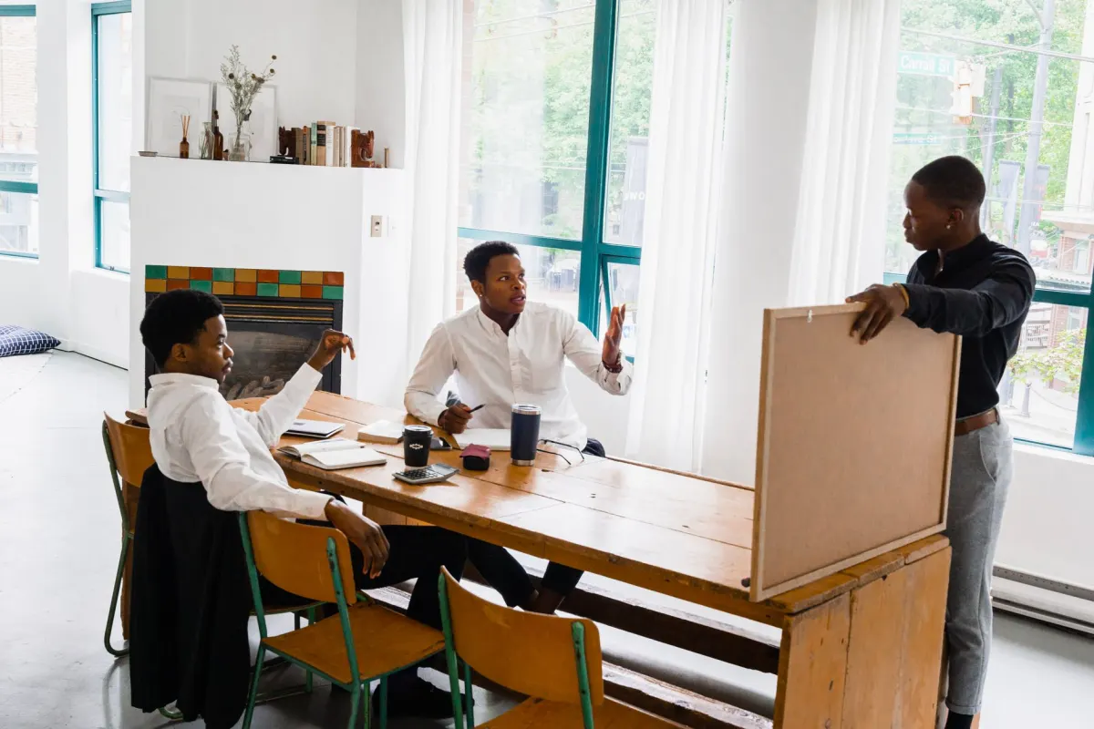 Ein kleines Team bespricht sich am Laptop, ein Bild fur den Moment, in dem eine Freelancerin beginnt, Unterstutzung ins Boot zu holen.