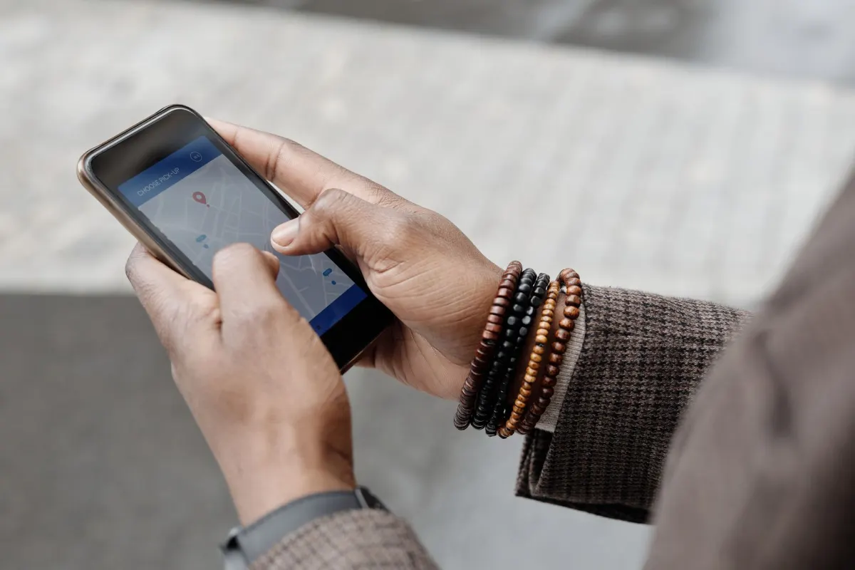 Uma pessoa segura um celular com um mapa aberto em uma rua da cidade, verificando um endereço específico em vez de uma área ampla.