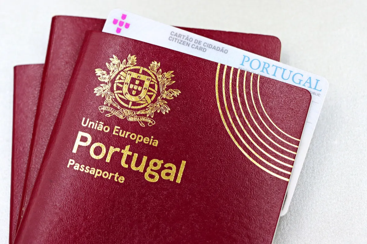Eine Person hält einen Reisepass neben einem Smartphone, stellvertretend für die für die Verifizierung erforderlichen Ausweisdokumente.