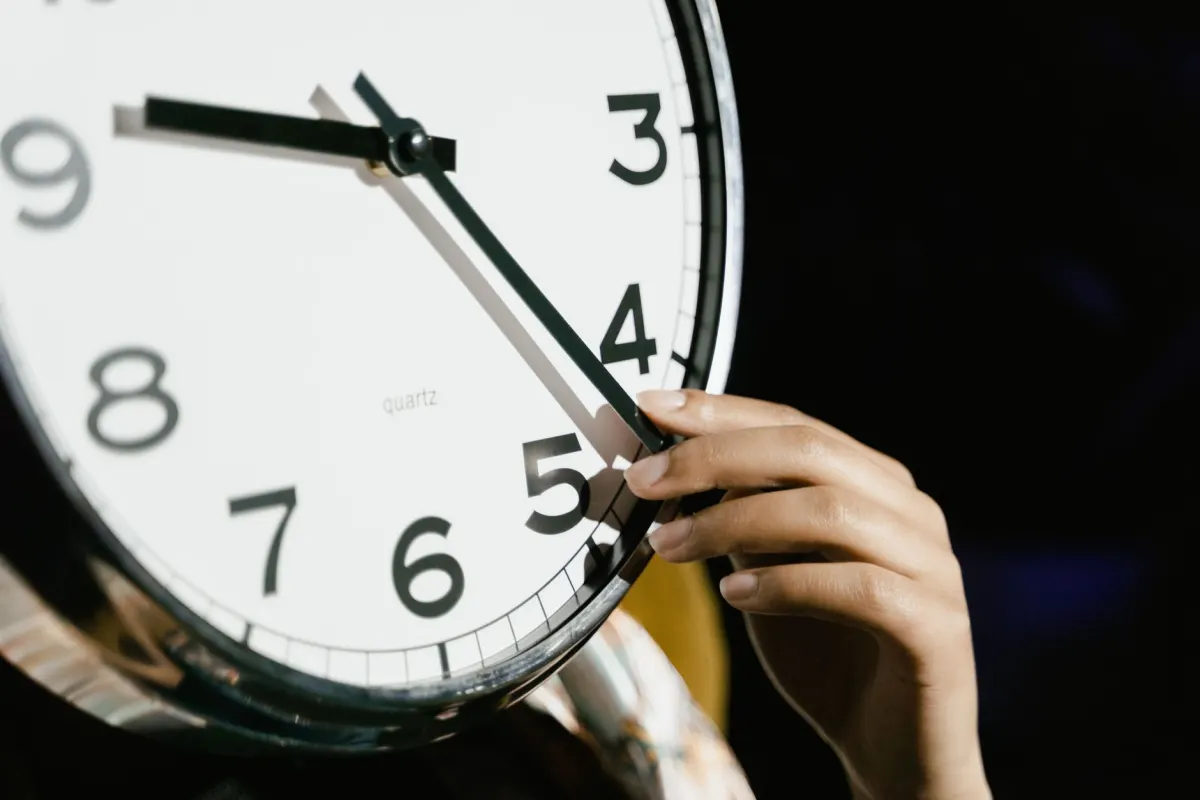 Eine Hand dreht am Zifferblatt einer Analoguhr vor, der Moment, in dem eine Stunde der Nacht verschwindet und ein geplanter Beitrag keine passende Uhrzeit mehr hat.