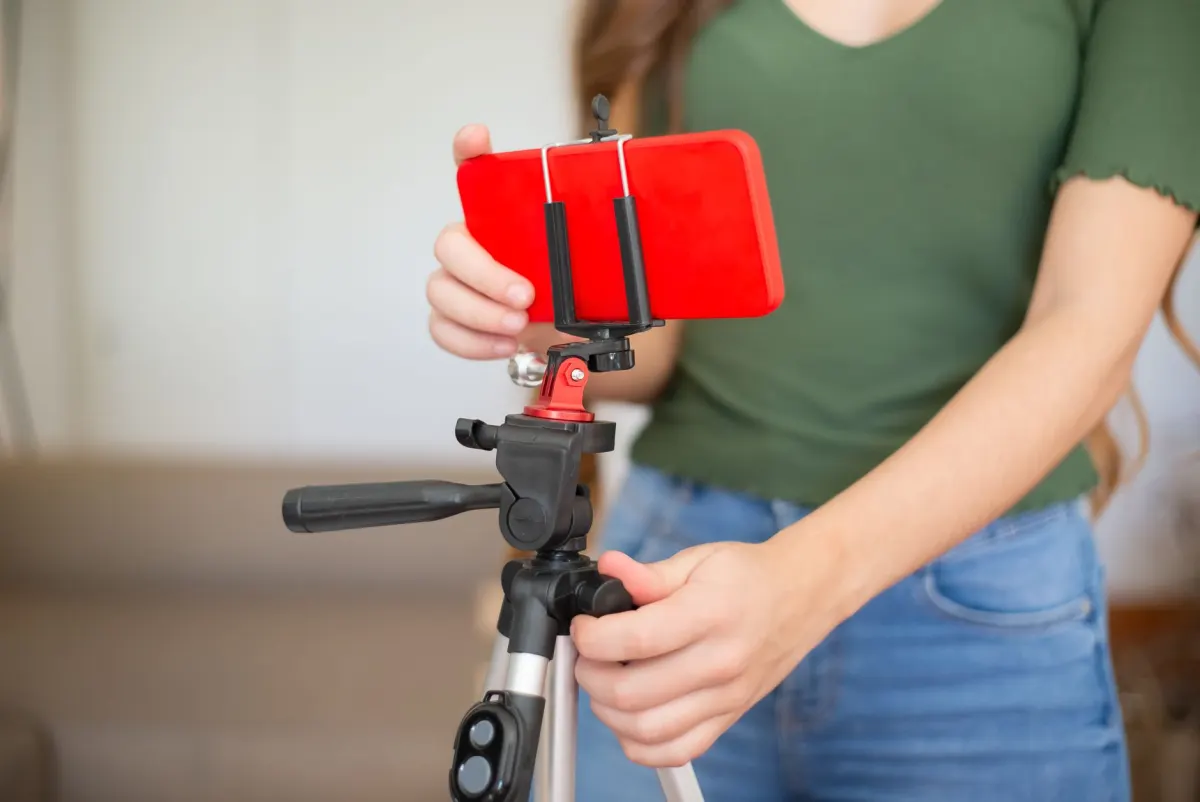 Une créatrice filme un tutoriel avec un téléphone monté sur un petit trépied, en accord avec la durée de 30 à 60 secondes recommandée pour le contenu éducatif.