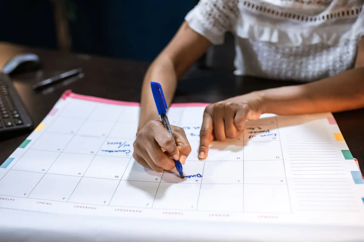 Uma pessoa planeja uma semana de publicações de vídeo em um calendário impresso, o tipo de agendamento em lote que torna sustentável um formato de Short de três minutos.