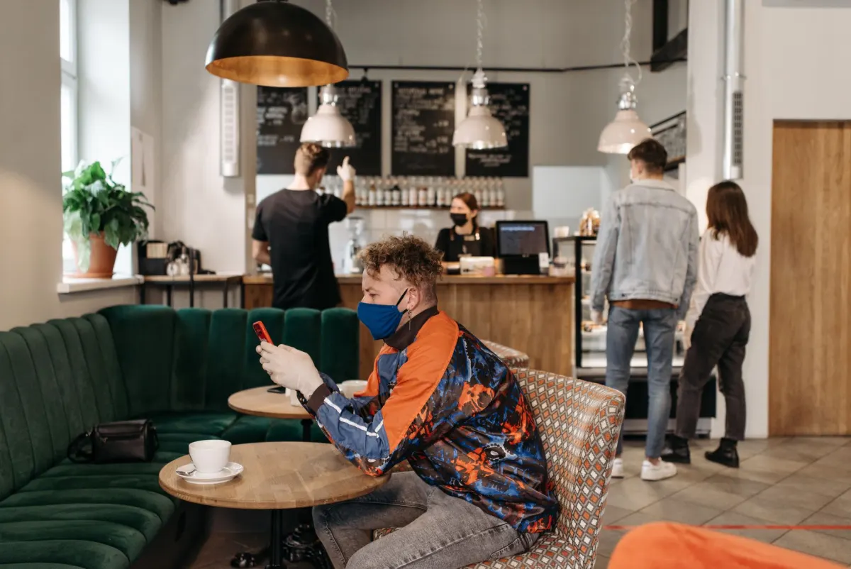 Eine Unternehmerin prüft an einem Cafétisch das Engagement auf ihrem Handy, passend zur Wachstumsphase mit Fokus auf Sichtbarkeit.