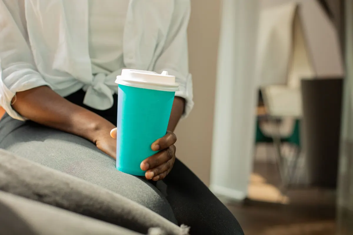 Une personne se détend avec un café loin de son bureau, illustrant les heures libérées grâce à l'automatisation des tweets.