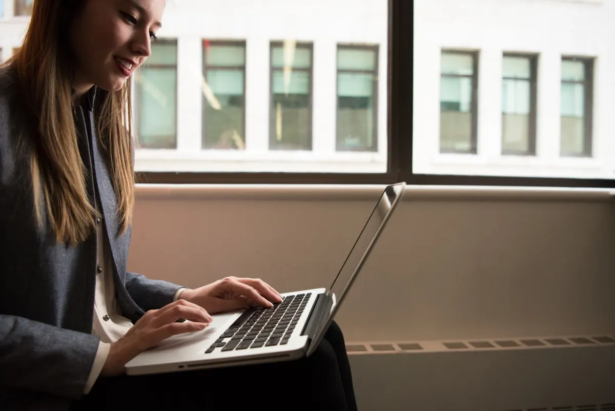 Eine Person lächelt beim Tippen auf einem Laptop, was die Gewohnheit widerspiegelt, kurz nach Veröffentlichung eines Videos auf Kommentare zu antworten.