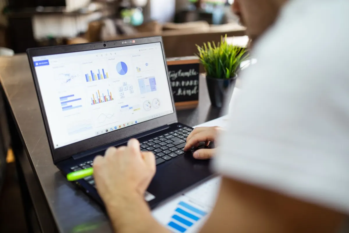 A laptop screen displays charts and graphs, the kind of performance data a creator digs through after posting.