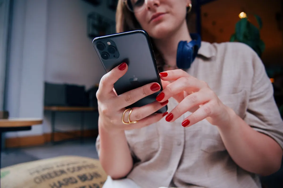 Uma mulher toca em um Story no celular, o lugar onde a figurinha de enquete é adicionada antes de publicar.