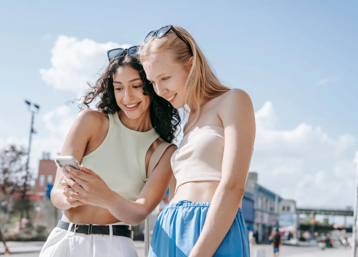 Amigos olham juntos para um celular, como quando se conferem os resultados da enquete antes do Story expirar.