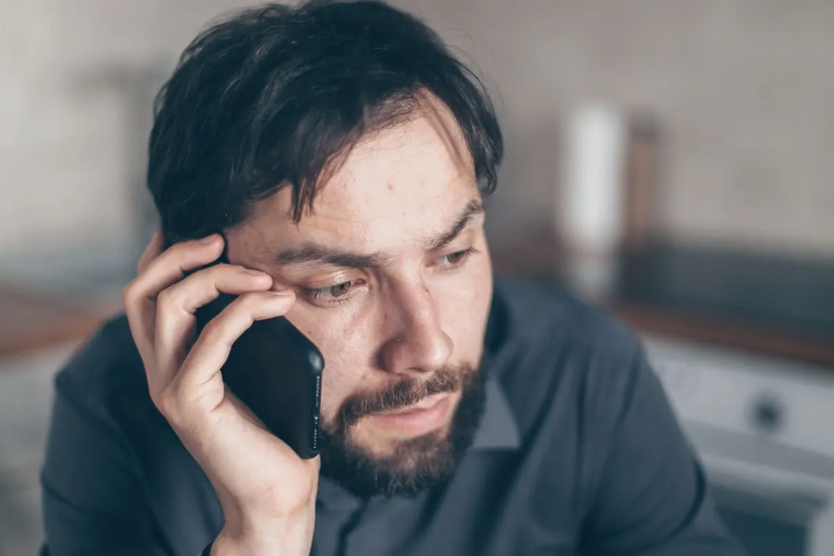 Eine Person blickt verwirrt auf ihr Smartphone und sucht nach einem fehlenden Symbol bei der Fehlerbehebung.