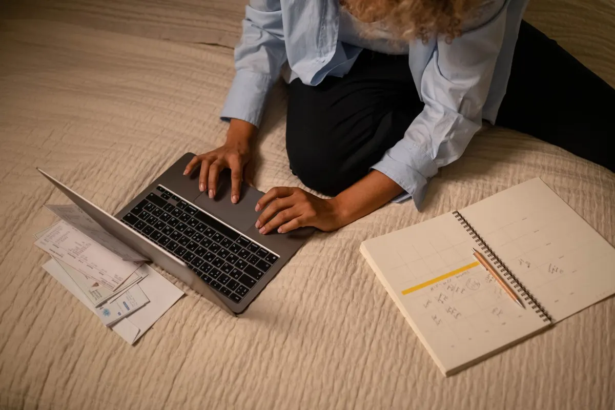 Eine Person überprüft an einem Schreibtisch einen Content-Kalender auf einem Laptop, was die Planungsarbeit hinter einer geplanten Pinterest-Strategie zeigt.