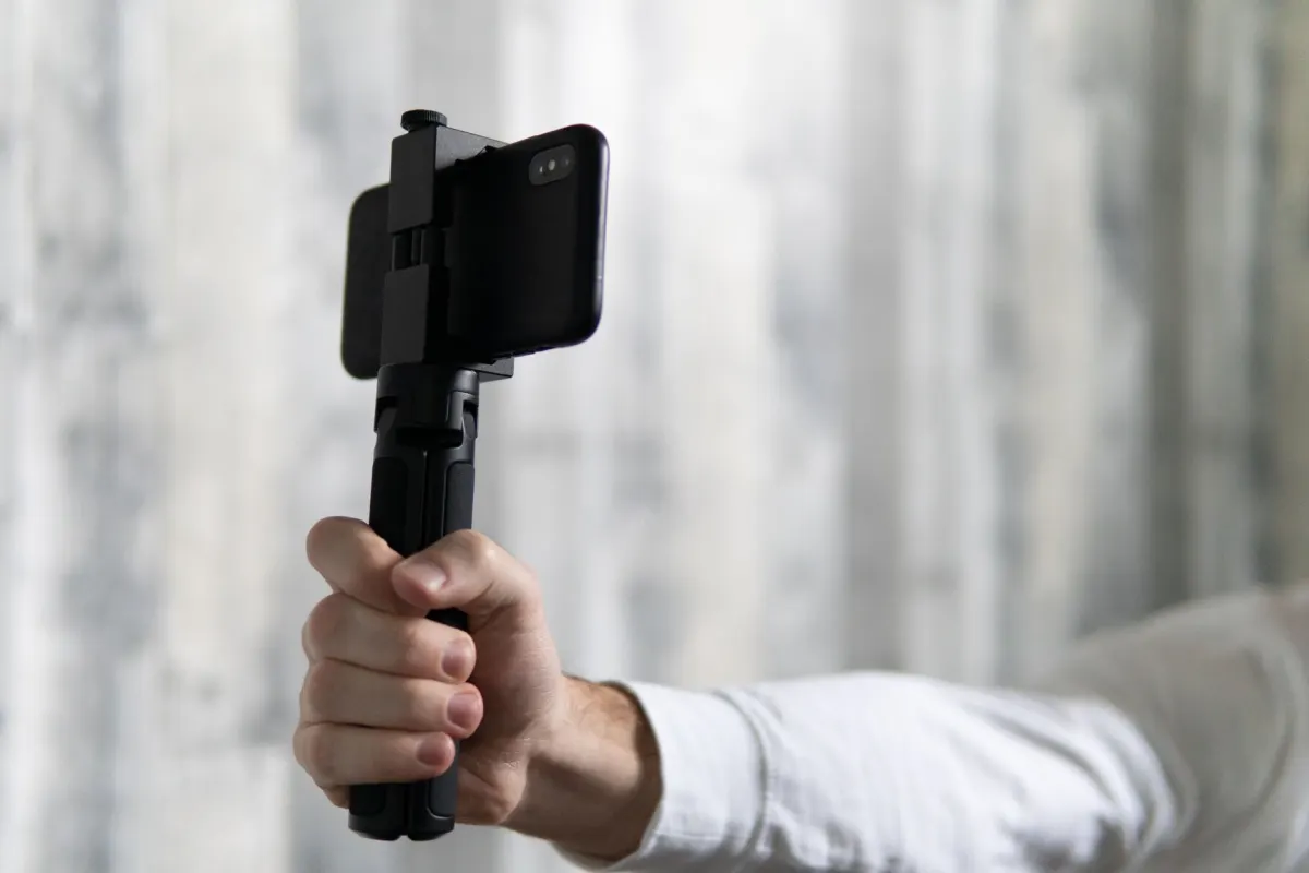 Ein Creator filmt ein vertikales Video mit einem Handy auf einem kleinen Stativ, die Art von Clip, die das in diesem Abschnitt beschriebene Tool auf mehreren Plattformen verteilt.