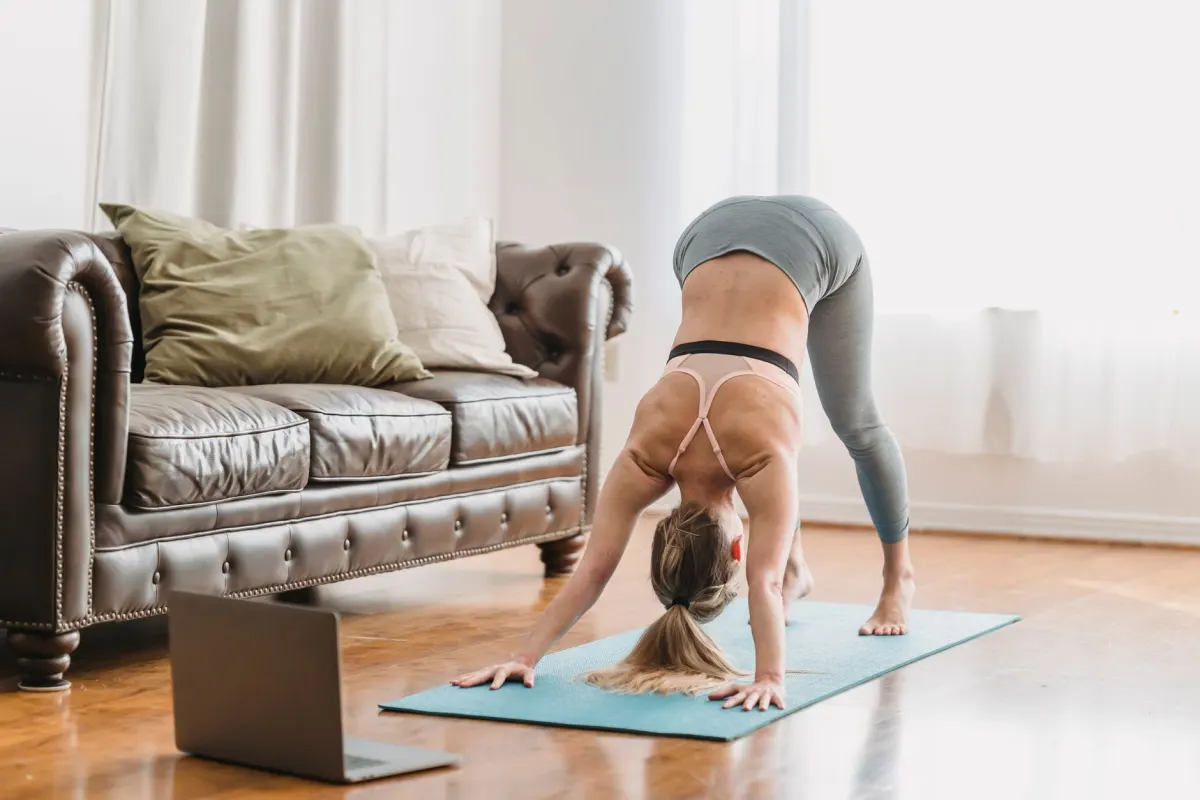 Eine Frau macht an einem Sonntagabend eine Yoga-Übung in ihrem Wohnzimmer, passend zum Wellness-Reset vor der neuen Woche.