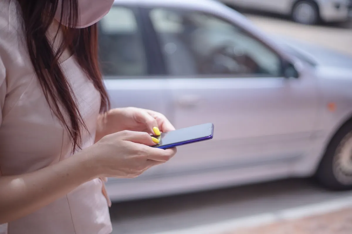 Eine Person prüft draußen ihr Smartphone, passend zum Thema mobile Warteschlangenkontrolle.