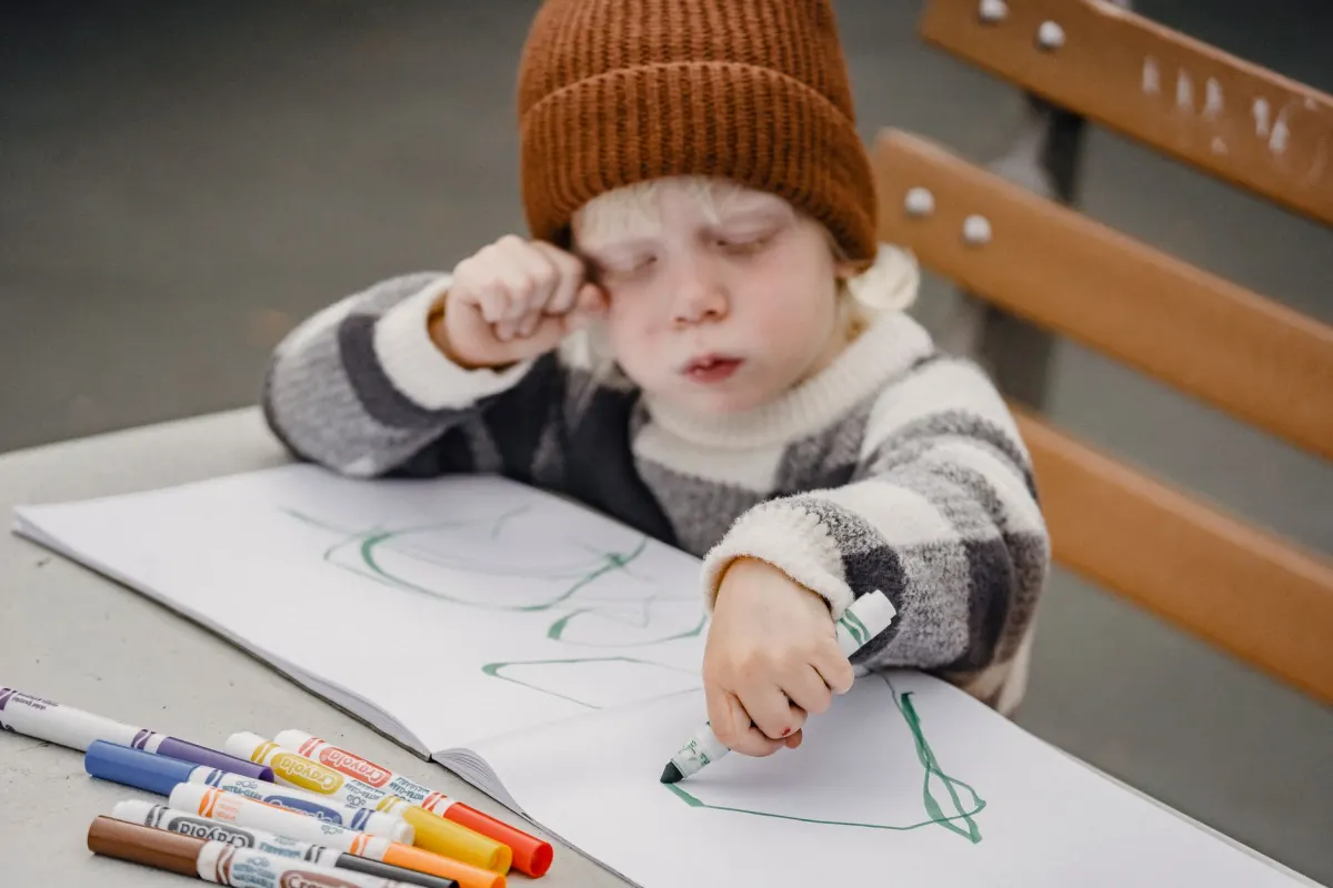 Ein Kind sitzt am Tisch und malt mit Filzstiften, ein Beispiel für Bastel-Inhalte, die sich gut für eine Kinder-YouTube-Nische eignen.